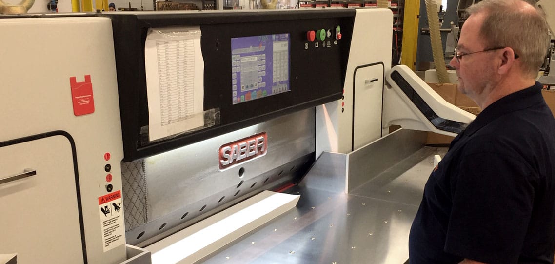 Joe Ward works on the new SABER paper cutter at The YGS Group in York, Pennsylvania.