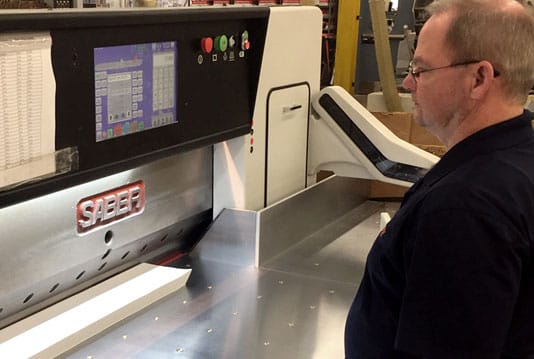 Joe Ward works on the new SABER paper cutter at The YGS Group in York, Pennsylvania.