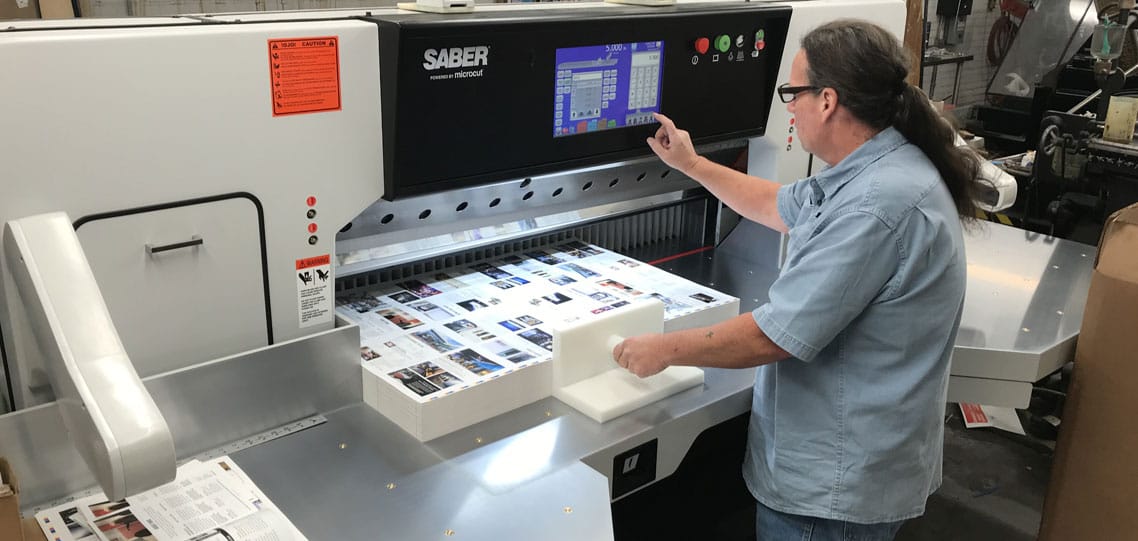 Kevin Chapman cuts work on the new 54-inch SABER X-15 paper cutter at MPress.