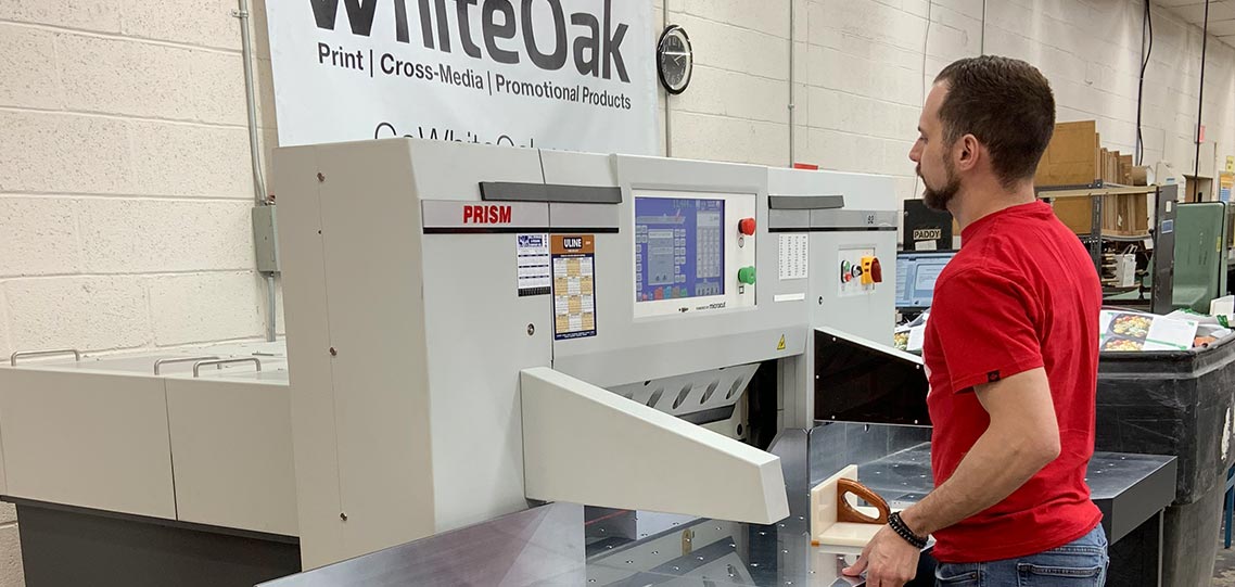 Brad Kaufman works on one of the new PRISM paper cutters at WhiteOak.