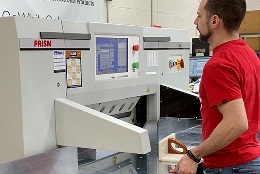 Brad Kaufman works on one of the new PRISM paper cutters at WhiteOak.