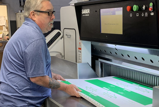 Worker operating a SABER paper cutting machine