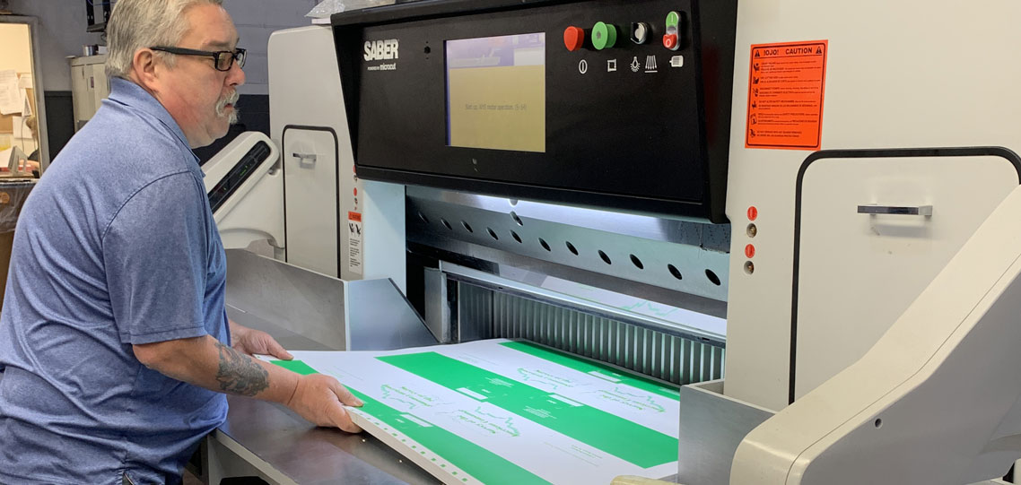 Worker operating a SABER paper cutting machine